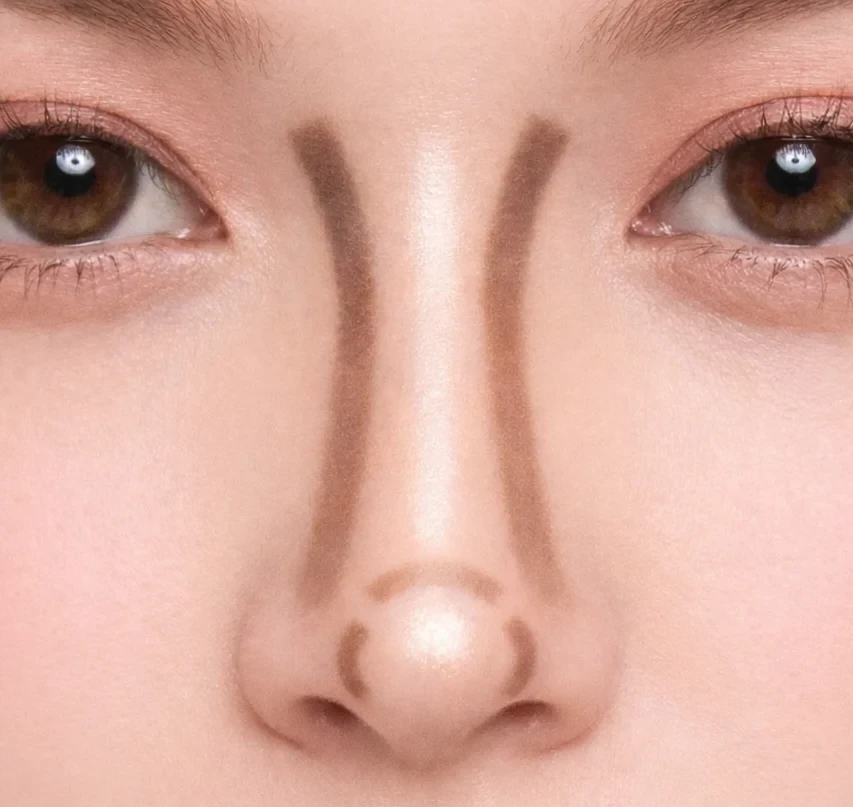 Gros plan sur un nez long avec contouring maquillage, lignes de contour foncées sur les côtés et anticerne clair au centre pour raccourcir visuellement le nez.