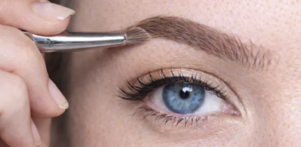 Estompage du maquillage des sourcils au pinceau biseauté pour un rendu fondu et naturel.