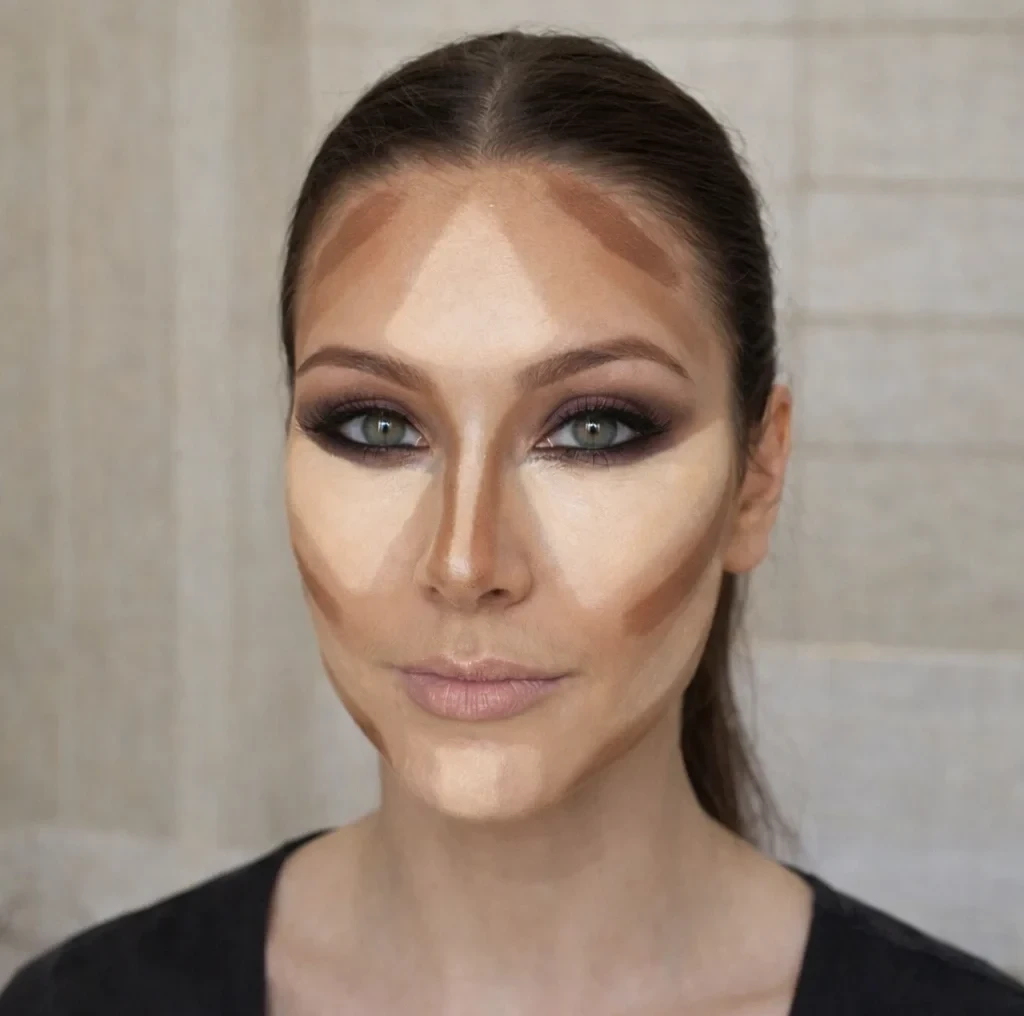 Application du contouring avec concealer : traits foncés et clairs placés sur le front, le nez et les joues pour structurer le visage, vue de face